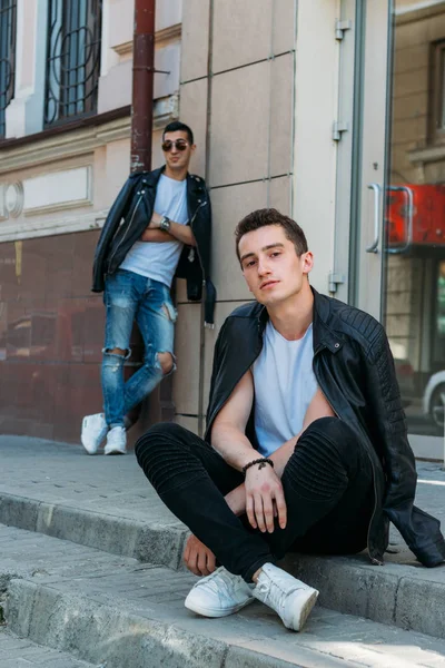 two attractive men are standing nearby, friends, posing, in black jackets and white T-shirts