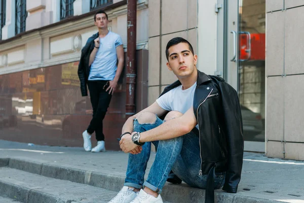 two attractive men are standing nearby, friends, posing, in black jackets and white T-shirts