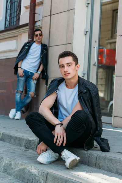 two attractive men are standing nearby, friends, posing, in black jackets and white T-shirts