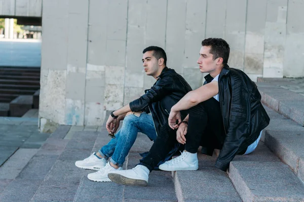Dois homens atraentes estão de pé nas proximidades, amigos, posando, em jaquetas pretas e camisetas brancas — Fotografia de Stock