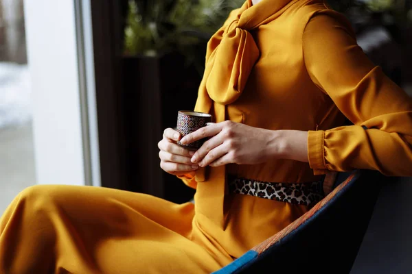 Дівчина в жовтій сукні сидить на стільці з кашею в руці, в приміщенні — стокове фото