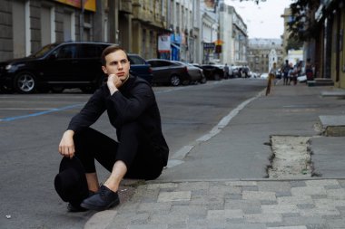 siyah bir şapka ile siyah bir adam asfalt yolda sokakta oturuyor.