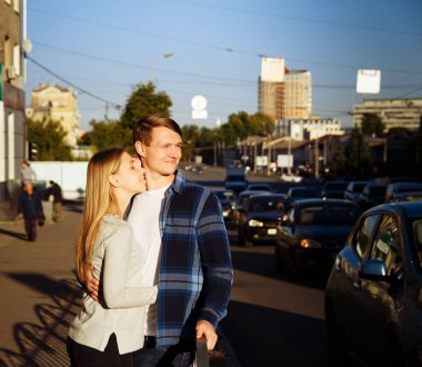 mutlu çift sokakta kucaklayan, yol yakınında. vagonun yanındaki çitin yanında durmak