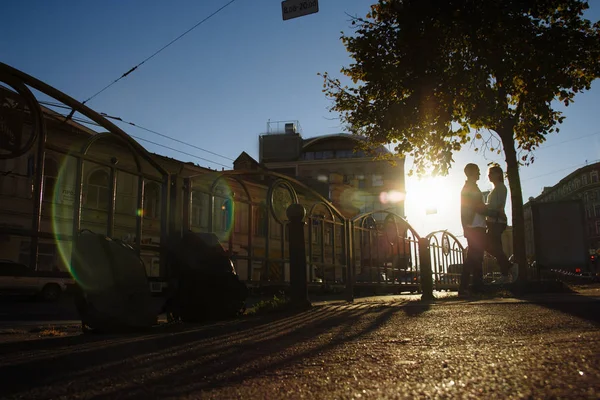 Coppia felice sta abbracciando in strada, i raggi del sole brillano sui loro volti, sfondo scuro. data in città — Foto Stock