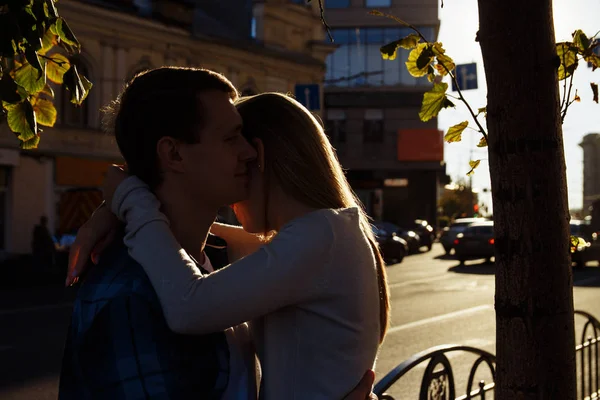 Coppia felice sta abbracciando in strada, i raggi del sole brillano sui loro volti, sfondo scuro. data in città — Foto Stock