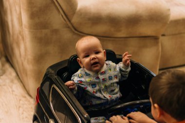 çocuk bir oyuncak arabada oturuyor, ve başlık üzerinde ikinci, çocuk oyunları