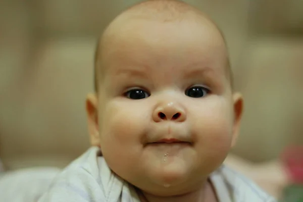 The baby is drooling, smiling at the camera. Close-up portrait — Stock Photo, Image