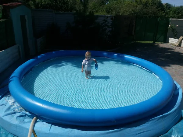 Ein kleines kind sitzt im pool und lächelt, spielt, die sonne scheint sommer — Stockfoto