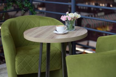 Ahşap masa arkasında bir fincan sıcak latte sanat kahvesi.