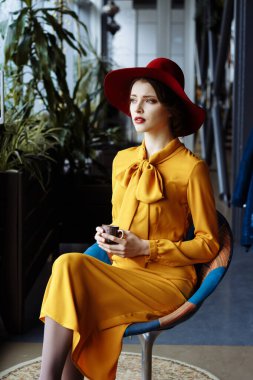 Kafede bir fincan kahve ve şapkalı bir kız. Sarkık şapkalı ve fiyonklu bluz giyen şehvetli bir genç kızın portresi. Kafede elinde kahve tutan güzel esmer kadın.