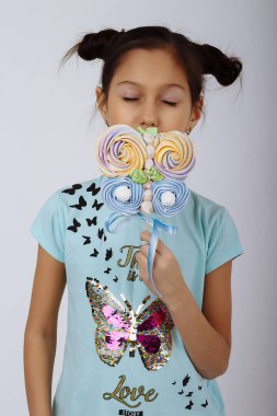 Bir kız elinde iki onları kameraya gösteren bir çubuk üzerinde çok renkli şekerler tutar. tatlı hayat