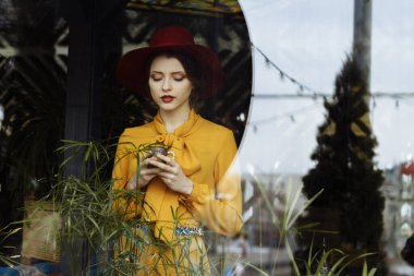 Kafede bir fincan kahve ve şapkalı bir kız. Sarkık şapkalı ve fiyonklu bluz giyen şehvetli bir genç kızın portresi. Kafede elinde kahve tutan güzel esmer kadın.