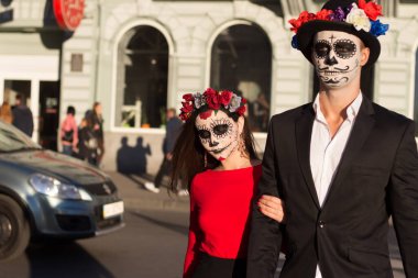 Kafatası makyajı yapan bir çift. Tüm ruhlar günü. Erkek ve kız şekeri kafatası makyajı cadılar bayramı için boyanmış. Şehirde ölü. zombi yürüyüşü.