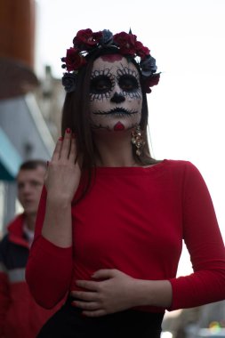 Kafatası makyajı yapan bir kadın. Ruhlar Günü. Kafatası şekeri kız. Cadılar bayramı için boyanmış. Şehirde ölü bulundu. Zombi yürüyüşü.