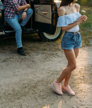 bir kız bir çiçek ve beyaz bir bluz, ekose gömlekli bir adam araba koltuğu arkasında oturan, bekleyen