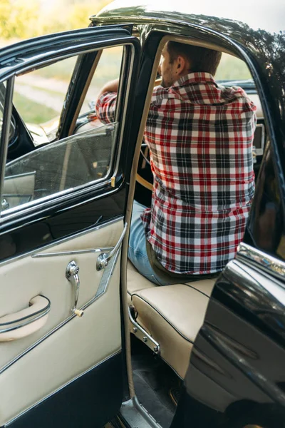 El hombre está sentado al volante, el conductor. vista desde la ventana trasera. Vista trasera del turista en coche. Conceptos de viajes y vacaciones de verano . — Foto de Stock