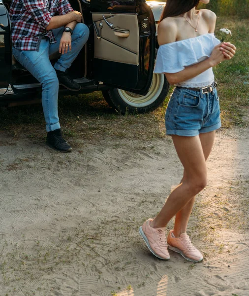 Uma menina com uma flor e em uma blusa branca, um homem em uma camisa xadrez está sentado na parte de trás do assento do carro, esperando — Fotografia de Stock