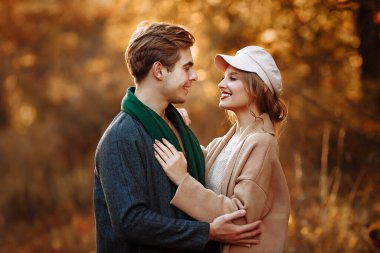 Mutlu, birbirine aşık çiftler sokaklarda sarılıp gülümsüyor, sonbahar, yeşil eşarp ve şapka, erkek ve kadın randevuda, sevgililer gününde. Parkta yürü