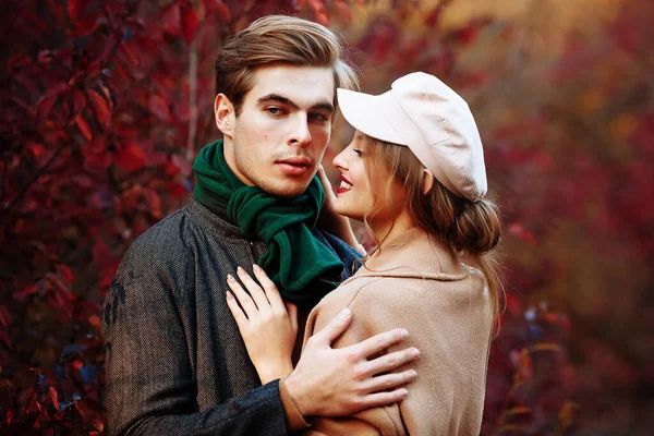 Felice, coppia innamorata abbracci e sorrisi per strada, autunno, sciarpa verde e cappello, uomo e donna su un appuntamento, giorno di San Valentino. passeggiata nel parco — Foto Stock