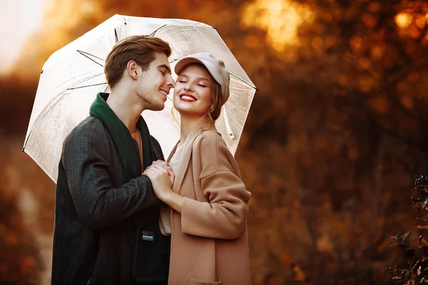 Feliz, pareja enamorada abrazos y sonrisas en la calle, otoño, bufanda verde y gorra, hombre y mujer en una cita, día de San Valentín. caminar por el parque —  Fotos de Stock