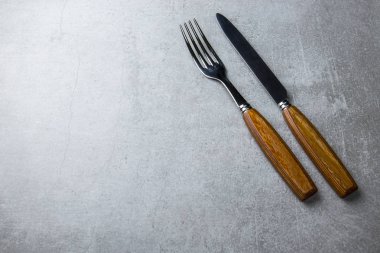 Çatal ve bıçakla gri bir arka plan üzerinde