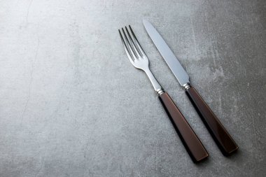 Çatal ve bıçakla gri bir arka plan üzerinde