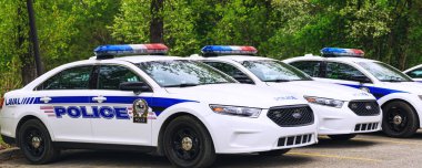 Laval, Canada: May 19, 2018. Police cars parked in the parking area of the public park. A lot of police cars stationed in line, before leaving to the mission.    clipart