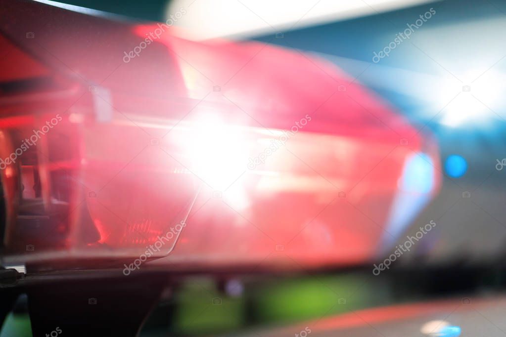 Red flashes on the car of the emergency vehicle at night. Police patrol car of the specialized unity in the night time. Police lights during traffic surveillance on the city road. Flash light on the cars of the force intervention department. 