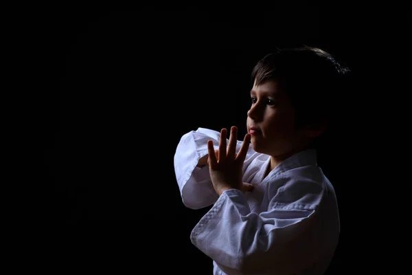 Beyaz kimono koyu arka plan üzerinde izole gerçek karate çocuk. Çocuk dövüş sanatları Dövüş için hazır. Judo eğitimi mücadele çocuk. 