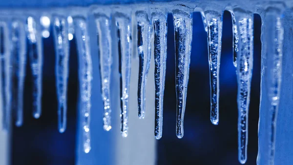Molti ghiaccioli e texture di cristallo su sfondo invernale. Le gocce d'acqua cadono da stalattiti in giorno di luce del sole. Scioglimento ghiacciolo durante il periodo primaverile . — Foto Stock