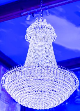 Zarif ve büyük parlaklık. Modern vintage iç lüks tiyatro avize. Yakın çekim resimde dallı süs Lambası fikstürü. Mavi arka plan üzerinde izole Glow Kristal Aydınlatma veya krom avize.