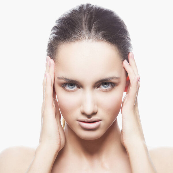 Portrait of young woman with natural makeup and hands near face on white background