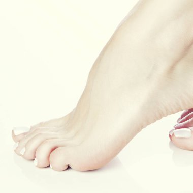 Beyaz arka plan üzerinde beyaz manikür ile ayak görünümü Kapat