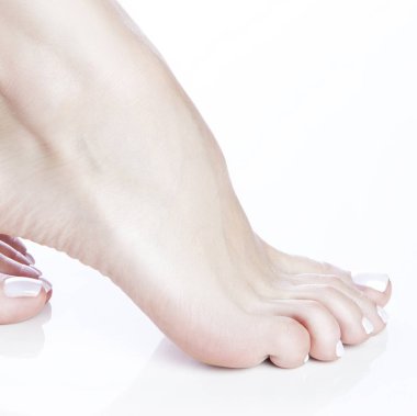 Beyaz arka plan üzerinde beyaz manikür ile ayak görünümü Kapat