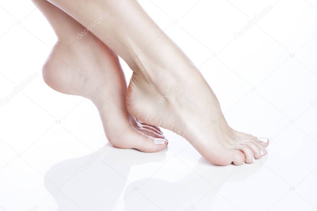 Close view of female feet with white manicure on white background