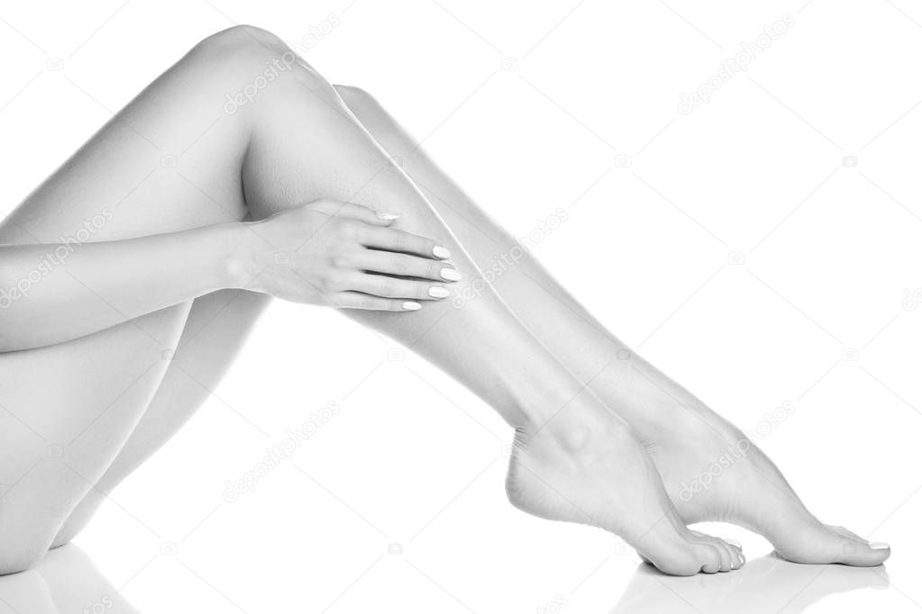 Side view of female feet and hand with white manicure on white background