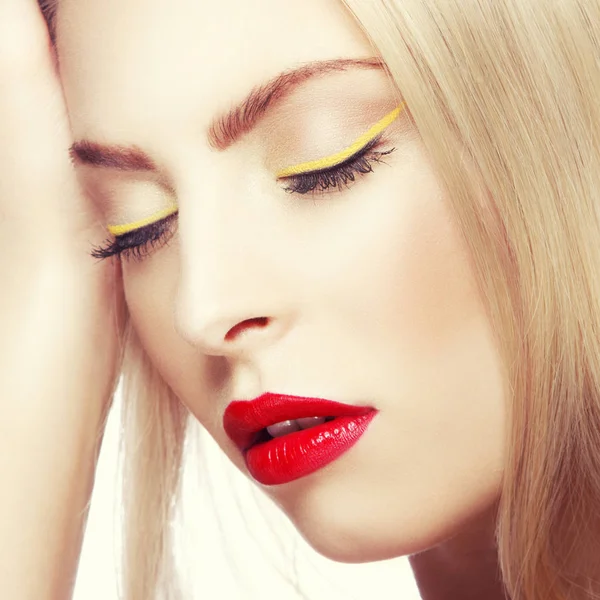 Portrait of woman with modern yellow eyeliner and red lips