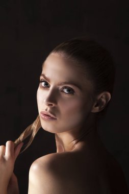 Siyah arka plan üzerine poz trendy doğal makyaj ile sarışın genç kadın