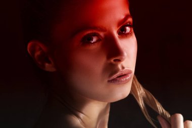 Genç sarışın model siyah arka plan üzerinde kırmızı ışık poz