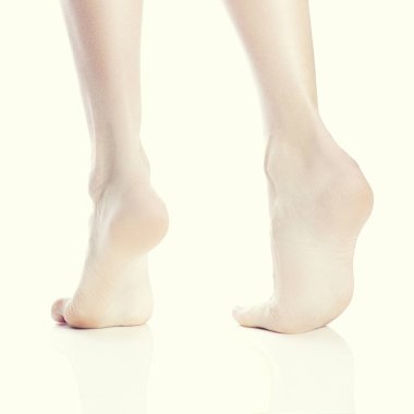 Beyaz arka plan üzerinde parmak ucunda duran kadın çıplak ayak arka görünümü