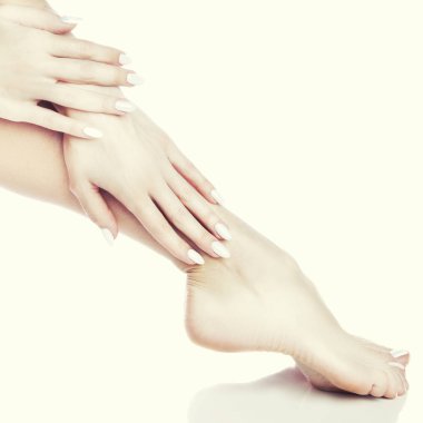 Beyaz arka plan üzerinde beyaz manikür ile ayak görünümü Kapat