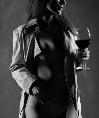 Kırmızı şarap kadehi. Bir kadeh şarabı olan genç bir kadın, seçici bir odak noktası. İç çamaşırı ve ceket giyen seksi bir kadın. Tek Renkli