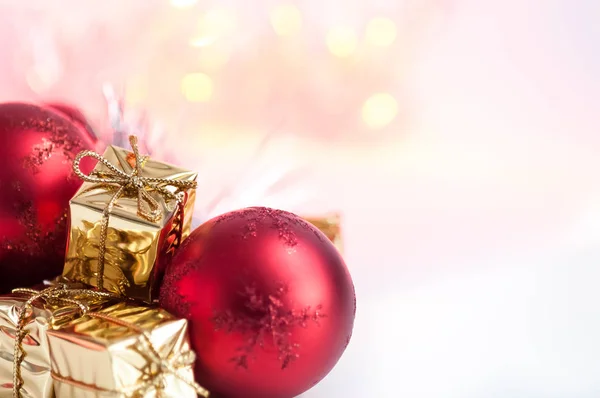 Merry Christmas, New Year, gifts in gold boxes, red Christmas balls are piled in the left corner. Background bokeh