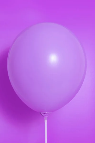 Purple balloon on a purple background with shadow. Side glare.