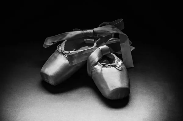 Pointe shoes ballet dance shoes with a bow of ribbons beautifully folded on a dark background.