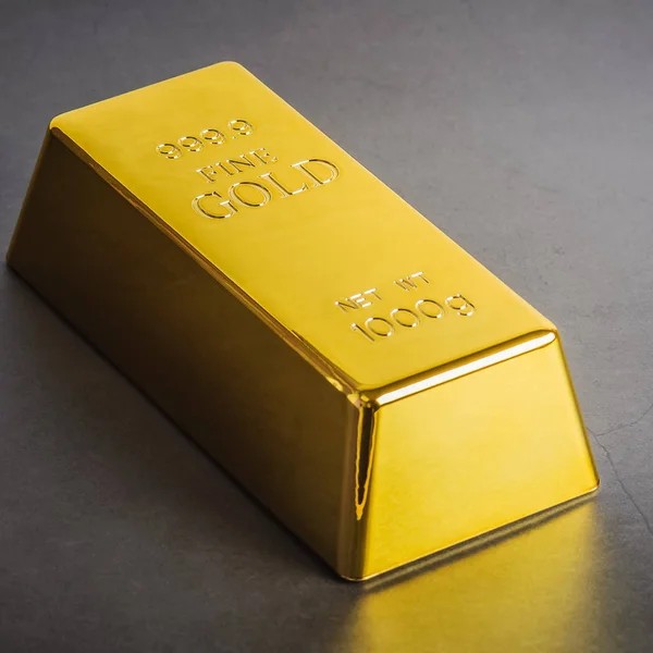 Gold bar ingot bullion on a gray background. Located diagonally.