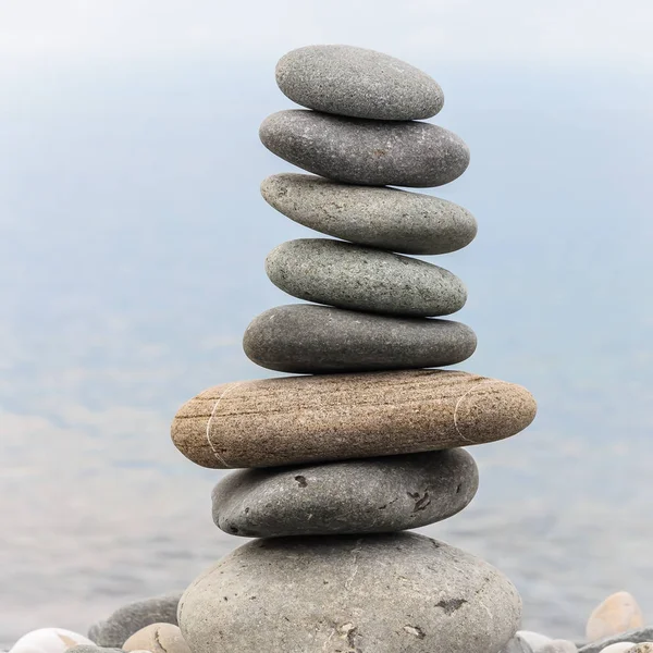 Pyramid of sea stones on pebbles of the sea shore. Seascape. The concept of balance and spirituality.