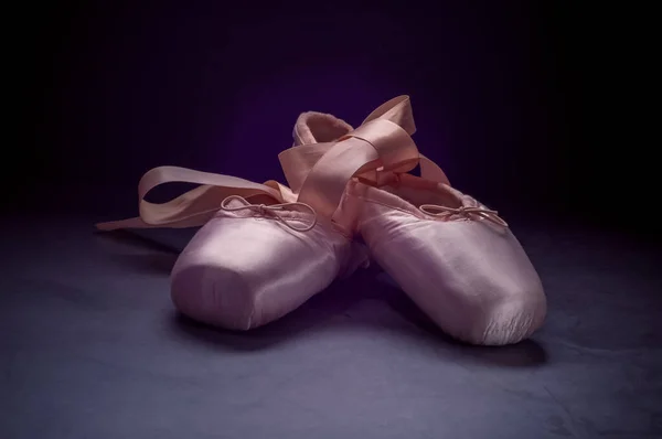 Pointe shoes ballet dance shoes with a bow of ribbons beautifully folded on a dark background.