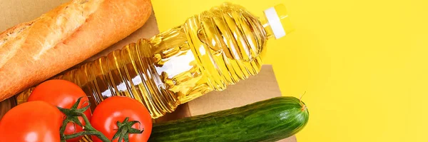 Cardboard box with food supplies for the period of quarantine isolation on a yellow background. Delivery, donation, coronavirus, copyspace.