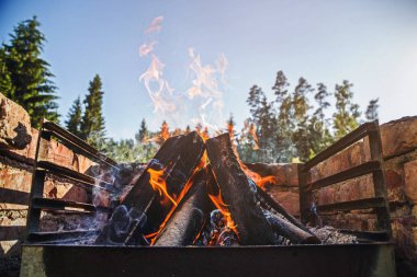 Güzel açık mavi ahşap günlükleri Barbekü Mangal yakma gökyüzünden yaz erken akşam içine yükselen alevler. Tonda.